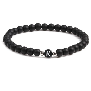 Detail of 6mm matte black stone beaded bracelet featuring silver spacers and letter K charm