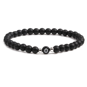 Detailed close-up of 6mm black matte stone beads with white letter O charm and silver spacers