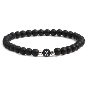Macro shot of 6mm matte black stone beads with letter X charm and silver metal accents