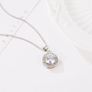 Detail of silver halo pendant necklace with round cubic zirconia on a white background