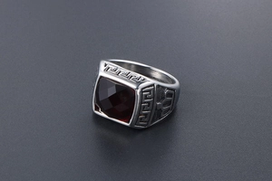 Detail of vintage men's silver ring with garnet-red stone and Greek key pattern