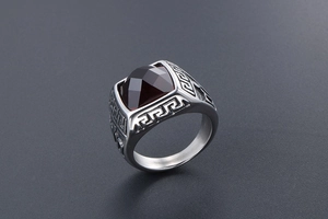 Detailed shot of silver titanium steel ring with engraved pattern and red gemstone