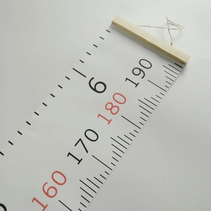 Close-up of fabric height growth chart featuring wooden hanger and printed numbers