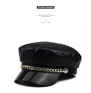 Detail shot of black faux leather baker boy hat with glossy brim and gold chain accent