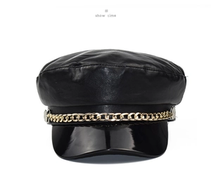 Detail of black faux leather newsboy cap with gold metal chain and shiny patent brim