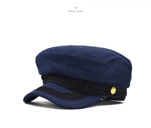 Detail of dark blue wool beret with black lace trim and golden vintage button accent