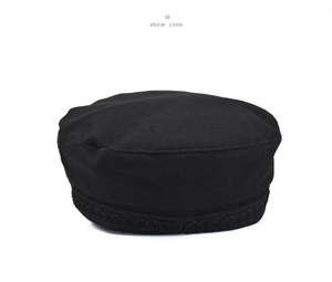 Detail of black wool newsboy cap featuring elegant floral lace embroidery trim