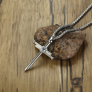 Detailed shot of silver stainless steel cross nail pendant on a natural stone surface