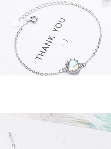 Detail of silver crown bracelet featuring iridescent moonstone on white background