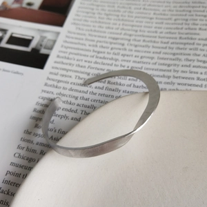Dettaglio macro del bracciale aperto minimalista in argento S925 con design opaco