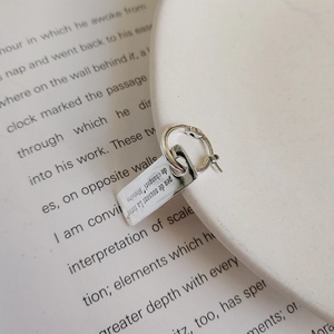 Macro detail of 925 sterling silver hoop earring with rectangular dream tag charm