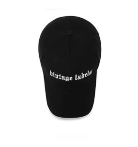 Top view of black cotton baseball cap showing white gothic vintage labels embroidery
