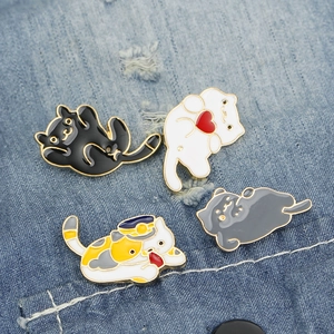 Set of four cute enamel cat brooches in various colors pinned on blue denim fabric