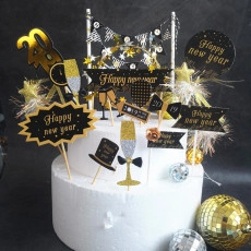 Macro shot of Black and Gold Happy New Year acrylic cake toppers on a white tiered cake