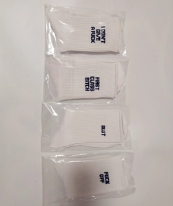 Flat lay of four white cotton socks with bold navy letter prints in individual clear packaging