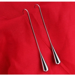 Detailed macro view of silver titanium steel water drop tassel earrings on red cloth
