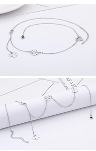 Detailed view of a silver metal anklet with elegant clover and heart shaped pendants