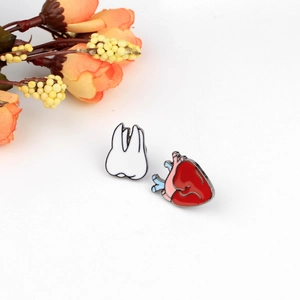 Creative enamel pin set featuring anatomical red heart and white tooth on white background