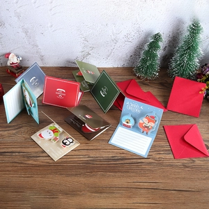 3D Christmas pop-up cards with cute cartoon characters and envelopes on wooden table