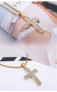 Détail du pendentif croix incurvée dorée avec zircons et chaîne corde torsadée