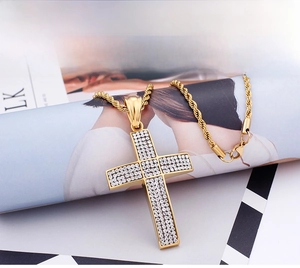 Gros plan du pendentif croix dorée sertie de diamants avec une chaîne torsadée