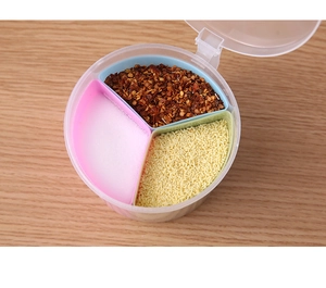 Detailed top view of a three-compartment plastic spice box on a wooden table surface