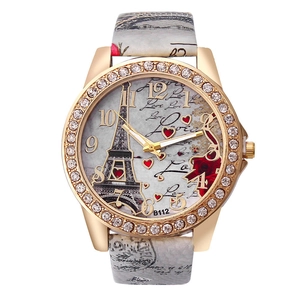 Close-up of rhinestone gold bezel watch featuring Eiffel Tower and Love floral dial