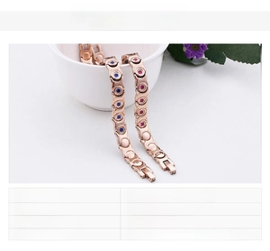 Detail of rose gold magnetic steel bracelet with red and blue stones in a white bowl