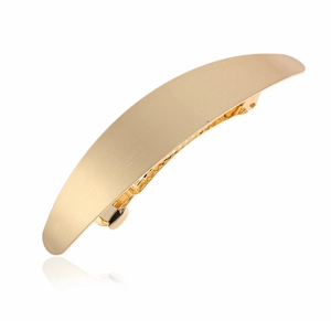 Detail of a matte gold curved metal hair clip with a sleek brushed finish texture