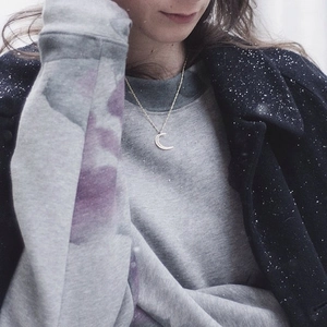 Silver crescent moon pendant necklace with rhinestones on grey sweatshirt