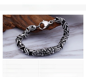 Detail of men's stainless steel skull bracelet with a heavy weave chain and lobster clasp