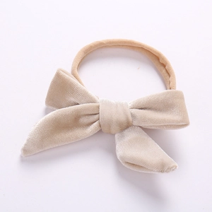 Detailed view of beige velvet baby headband with soft nylon bow on white background