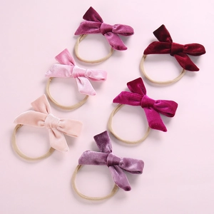 Set of six velvet bow baby headbands in assorted pink and purple shades on soft background