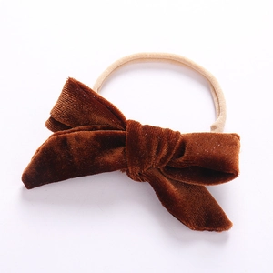 Close-up of soft brown velvet bow on a seamless nude nylon headband for infants