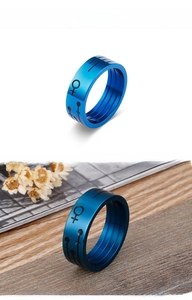 Blue titanium steel ring detail with gender symbols on a decorative wooden background