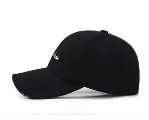 Detail view of black woolen baseball cap with white cursive embroidery on side panel