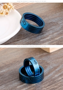 Close-up of blue titanium steel couple rings with engraved gender symbols on wood
