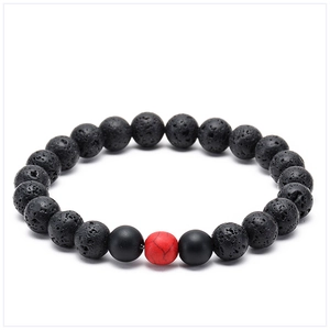 Macro detail of natural lava rock beads and black matte stone bracelet with red accent