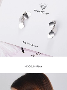 Detail of silver disc drop earrings on a card and worn by a model in a Korean style