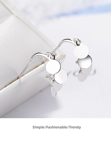 Detail of silver drop earrings with three polished overlapping metal discs on jewelry box