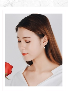 Close-up of minimalist white pearl stud earrings shown on a model for a refined look