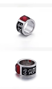 Macro detail of men's stainless steel ring with red stone inlay and Sanskrit engraving
