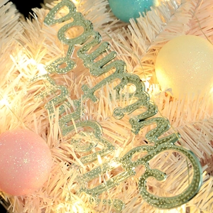 Glittery Merry Christmas sign ornament on a decorated tree with warm LED lights
