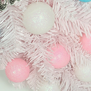 Pink and white macaron ornaments hanging on a white artificial Christmas teardrop tree