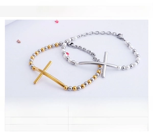 Detail of silver and gold beaded cross bracelets with pearls on white background