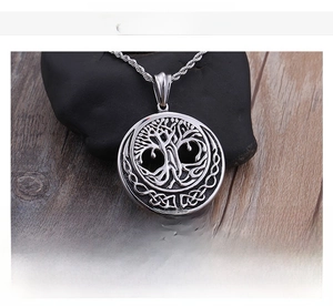 Macro detail of stainless steel Tree of Life pendant with vintage chain on textured stone