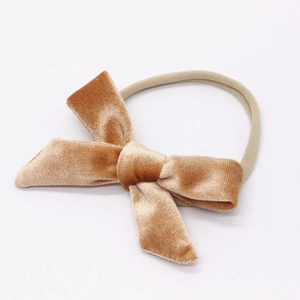 Detail showing soft velvet baby bow and seamless nylon headband in beige on white background