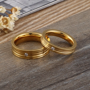 Minimalist gold-plated couple rings with rhinestone accents on a grey textured base