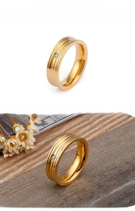 Detail of gold minimalist ring with triple parallel grooves and a centered round zircon