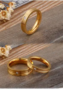 Detail of gold couple rings with vertical grooves and single zircon on dark wood